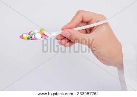 Doctor Holding Out Pills On Spoon On White