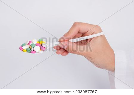 Doctor Holding Out Pills On Spoon On White