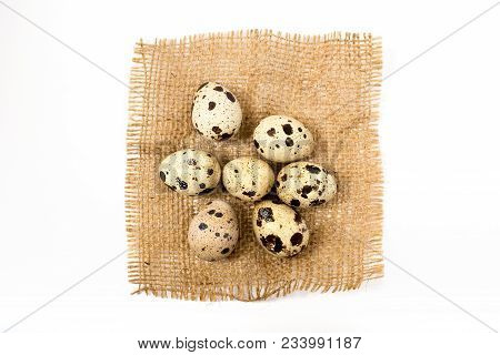 Seven Quail Eggs On The Burlap And On The White Bacground