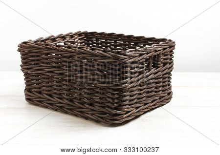 Empty Wicker Brown Rattan Basket On A White Wooden Background And White Wall. Natural Eco Handmade I