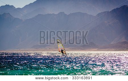Surfer Ride In The Sea On The Background Of The Rocky Coast In Egypt Dahab