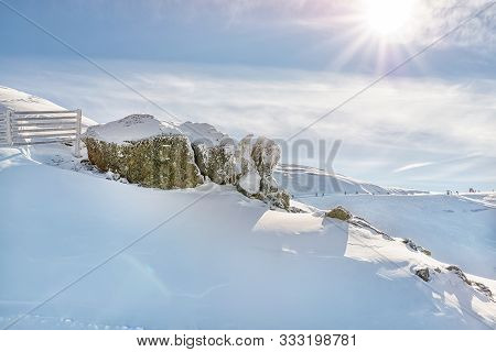 Scenic Alpine Mountain Peak Covered With Thick Snow Layer With Rocks And Fence Defense From Avalanch