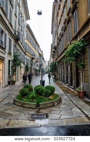 Italy, Milan - Ocrober 7, 2014: Street Among Ancient Houses With Pedestrians And Green Plants
