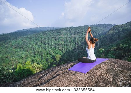Asian Women Relax In The Holiday. Play If Yoga. On The Moutain Rock Cliff. Nature Of Mountain Forest