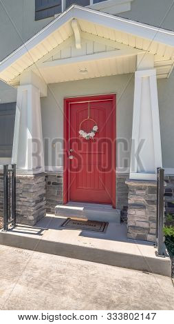 Vertical Piched Roof Over The Vivid Red Front Door With Pillars And Railing On Both Sides