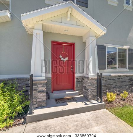 Square Frame Piched Roof Over The Vivid Red Front Door With Pillars And Railing On Both Sides