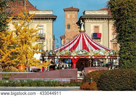 ALBA, ITALY - OCTOBER 24, 2020: Carrousel on the town square among trees with yellow leaves during famous annual White Truffles Festival in small town of Alba in Piedmont, Northern Italy .