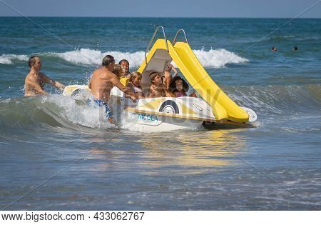 Family On A Marine Pedal Catamaran Trying To Land Across The Waves At Marina San Nicola Beach In Ita