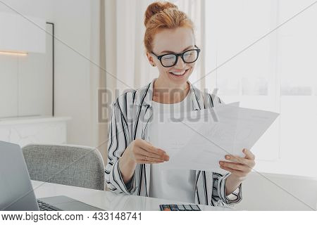 Happy Smiling Caucasian Woman Reading Good News In Financial Documents While Managing Family Budget,