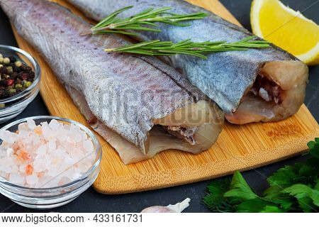 Close-up Raw Pollock Fish. Uncooked Pollock On Wooden Cutting Board With Ingredients For Cooking On 