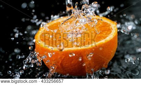 Freeze Motion Shot of Fresh Orange with Water Splash, close-up.