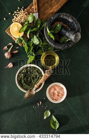 Pesto Sauce In Bowl With Ingredients On Rustic Green Table. Traditional Italian Pesto Recipe For Mak