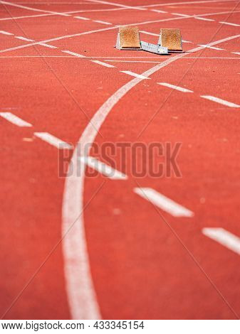 Empty Starrting Blocks At Cindertrack Of Athletics Stadium. Runner Tracks Painted On Red Tamrac