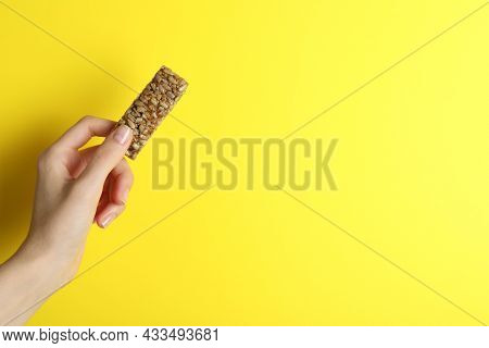 Woman Holding Kozinaki Bar On Yellow Background, Closeup. Space For Text