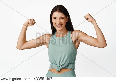 Strong Beautiful Woman Flexing Biceps, Showing Muscles On Arms And Smiling Happy, Bragging With Fit 
