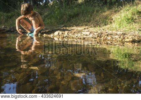 Little Boy Exploring Clear Mountain Riverside. Selective Focus On Riverbed