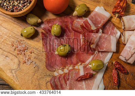 Meat, Ham With Herbs And Spices On Wooden Background. Schwarzwald Ham With Green Olives. Thinly Slic