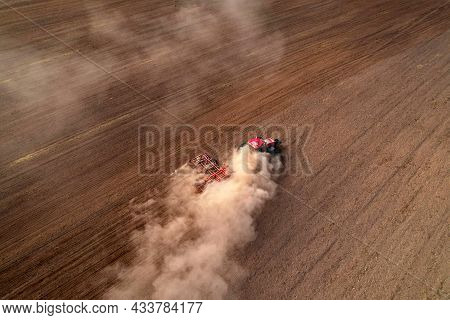 Agricultural Tractor On Cultivating Field For Sowing Seeds. Farming And Seeding Concept. Seed Sowing