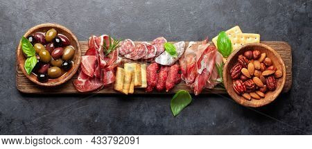 Antipasto board with prosciutto, salami, crackers, cheese, nuts and olives. Top view flat lay with copy space