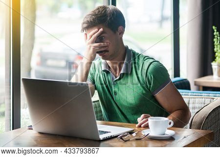 Spy, Shy Or Afraid. Young Businessman In Green T-shirt Sitting Try To Looking At Laptop Display Thro