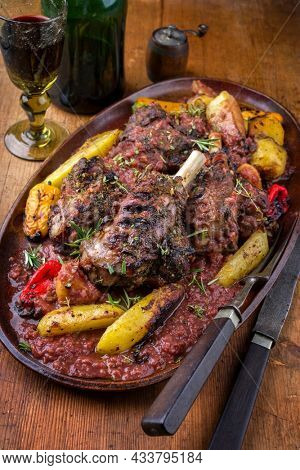Traditional French slow coocked lamb knuckles with fried potatoes in burgundy sauce offered as close-up on on a design plate