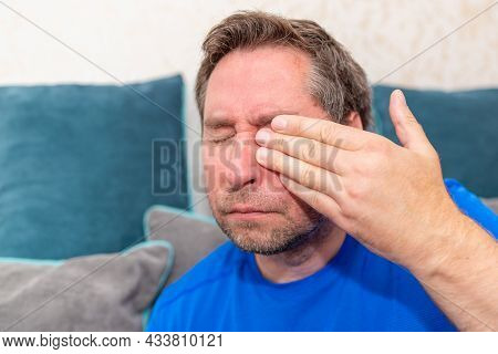 Middle Aged 45s Man Holding Hand Over His Aching Eye At Home On The Couch.closeup.