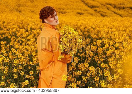 Portrait Of Red Haired Women Dressed In Trendy Fall Orange Trench Coat In Colourful Orange Field. Fa