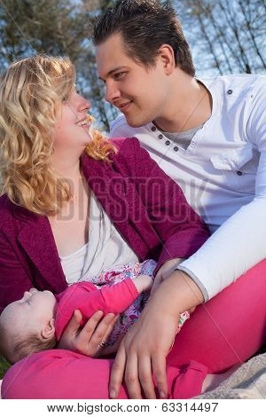 Smiling Couple And Their Sleeping Baby Girl