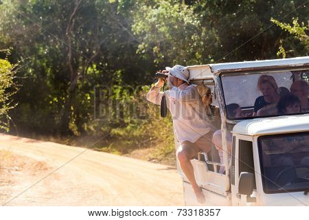 YALA NATIONAL PARK, SRI LANKA - MARCH 4, 2014: Tourist looking through binoculars during safari tour in the Yala park. Yala is the second largest national park in Sri Lanka.