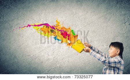 Young boy splashing colorful paint from bucket