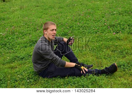 Man sitting on the grass with a phone in her hands