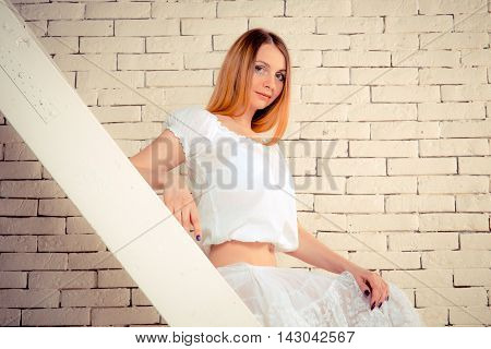 Girl sit on stairs on brick wall baclground
