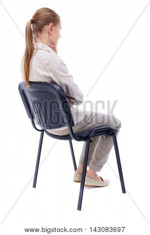 back view of young beautiful  woman sitting on chair.  girl  watching. Rear view people collection.  backside view of person.  Isolated over white background. Skinny girl in white denim suit sidit
