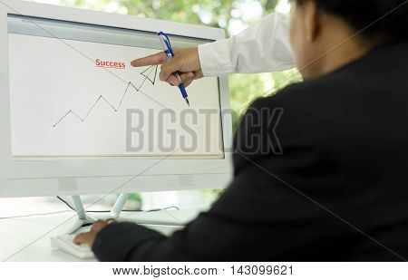 Business people look at graphs and charts being demonstrated on the screen of computer
