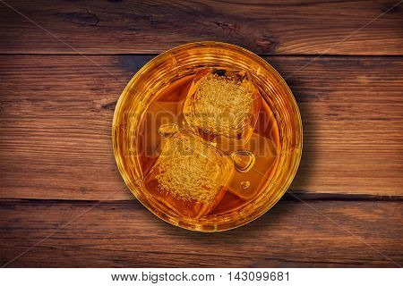 Top Of View Of Whiskey In Glass With Ice Cubes On Wood Table Background