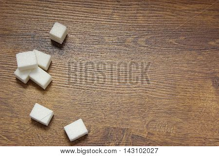 Sugar cubes on a wooden table top view. Place for text.