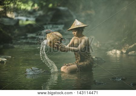 Asian girls are washing basket in a stream Thailand