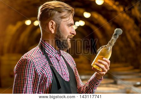 Sommelier holding old bottle of white wine with famous black mold in a wine cellar in Hungary