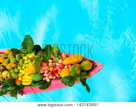 The exotic tropical fruits on the boat canoe against blue water