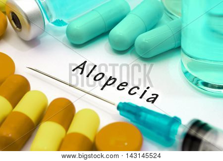 Alopecia - diagnosis written on a white piece of paper. Syringe and vaccine with drugs.