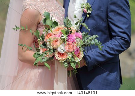 Beautiful bridal bouquet in hands of the bride. Wedding bouquet of peach roses by David Austin single-head pink rose aqua eucalyptus ruscus gypsophila