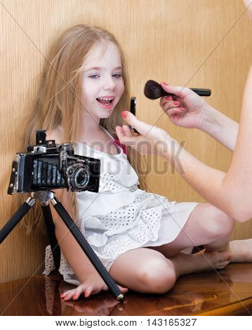 Litte girl befor photo shoot near wall