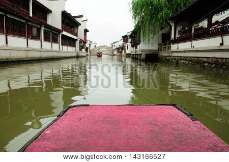 The front of a Chinese tourist boat on the water canals of Zhaojialou in Shanghai china on an overcast day.