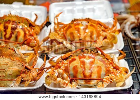 Buy seafood on the traditional asian street night market. Plenty of steamed crabs being tie for sell