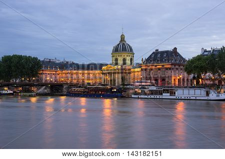 The French Institute and Pont des Arts across the Seine river at night Paris France