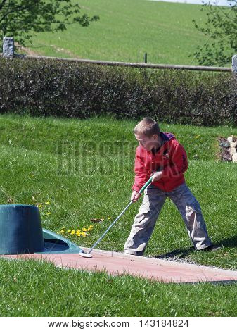 Little boy trying to play golf on vacation