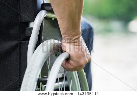 Close-up Of A Disabled Man Pushing Wheel Of Wheelchair