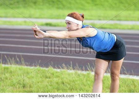 Young Red Haired Ginger Caucasian Female in Athletic Sportgear Making Arms Stretching Excercises Outdoors. Horizontal Image