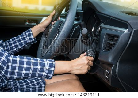 Women driver hand inserting car key and starting engine.