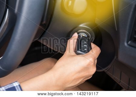 Women driver hand inserting car key and starting engine.